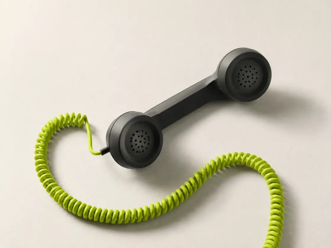 Conceptual still life: a charcoal telephone handset with a lime cord, representing conversation